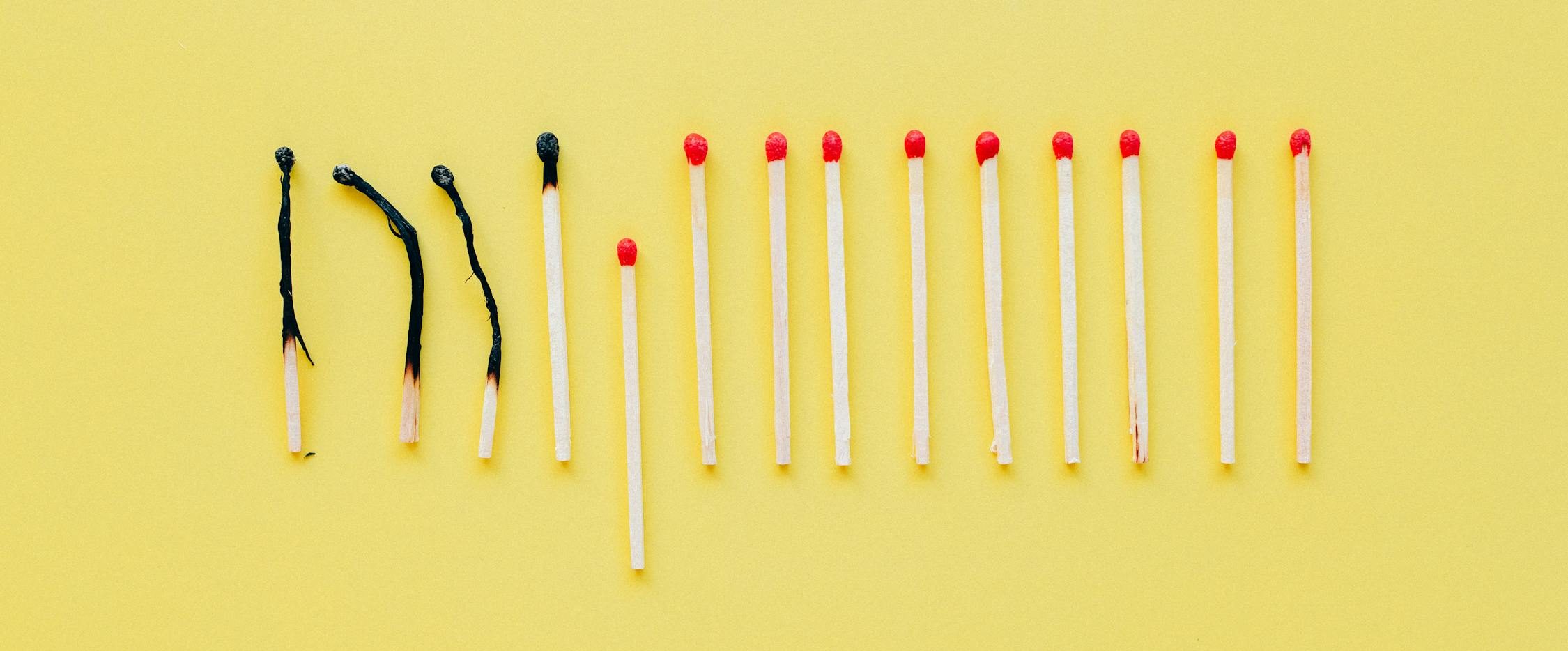 Burnt and unburnt matches on a yellow background symbolising fire prevention and the importance of breaking the chain of fire spread — fire safety concept image
